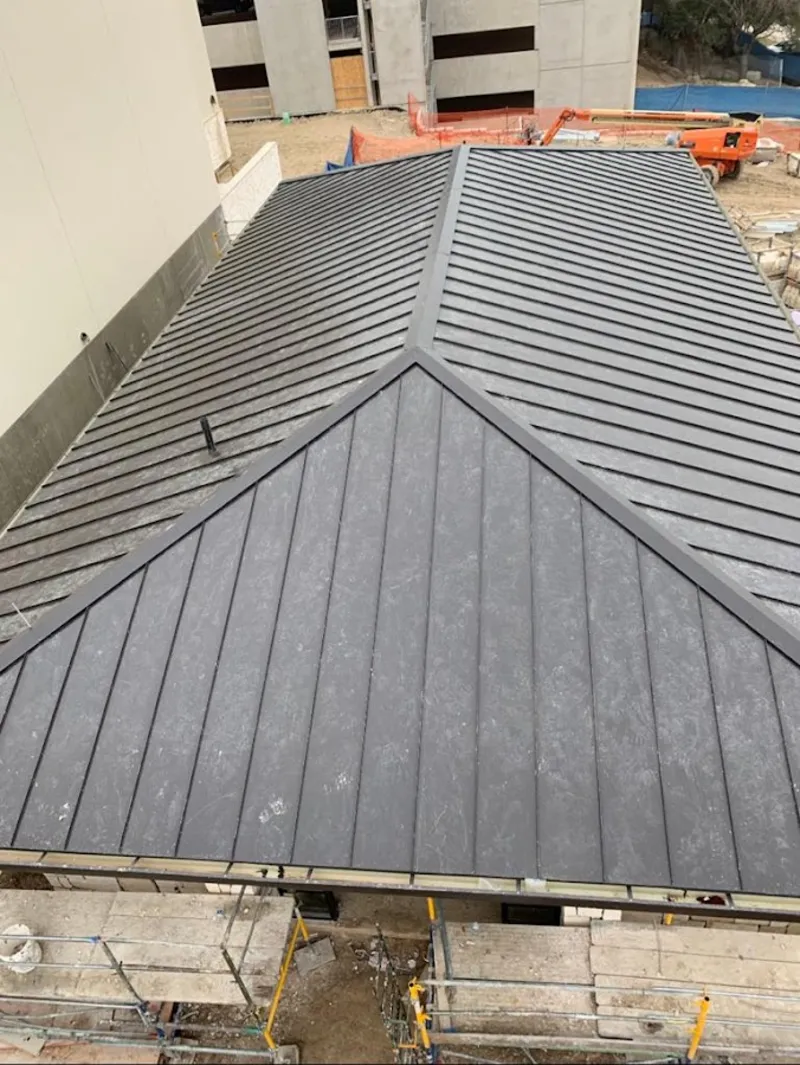 Commercial metal roof construction with crane equipment in Montebello